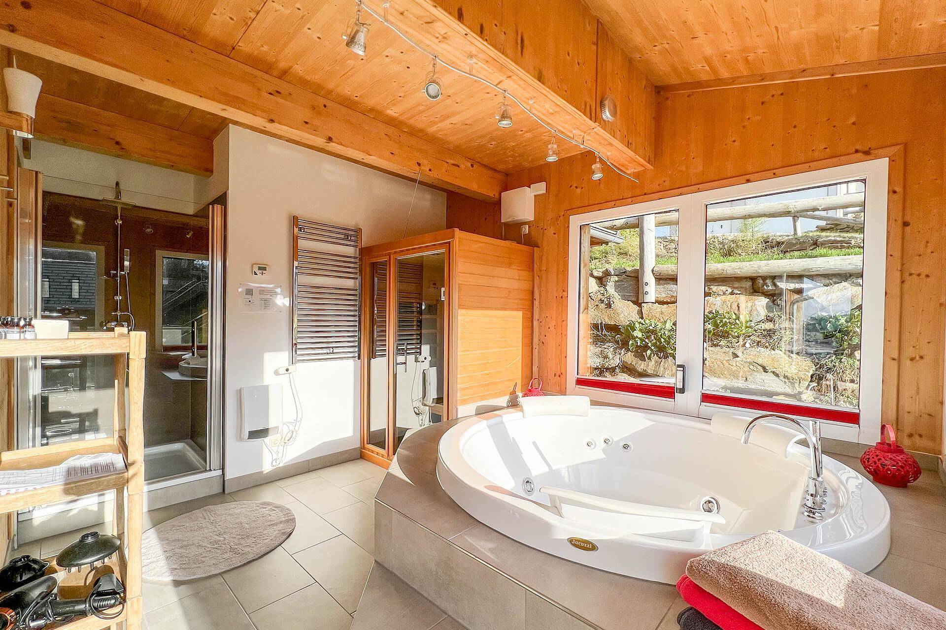 Luxuriöses Badezimmer mit Whirlpool, integrierter Sauna und großen Fenstern.