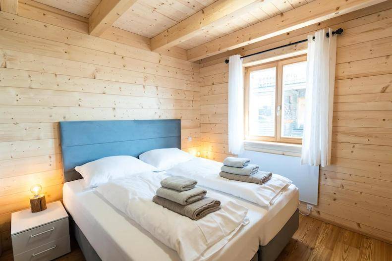 Gemütliches Schlafzimmer mit Holzwänden, Doppelbett und Holzboden.