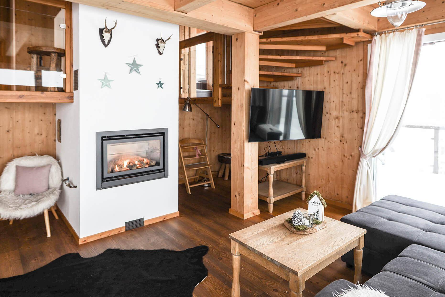 Wohnzimmer mit integriertem Kamin, Holzwänden und einem modernen Flachbildfernseher.