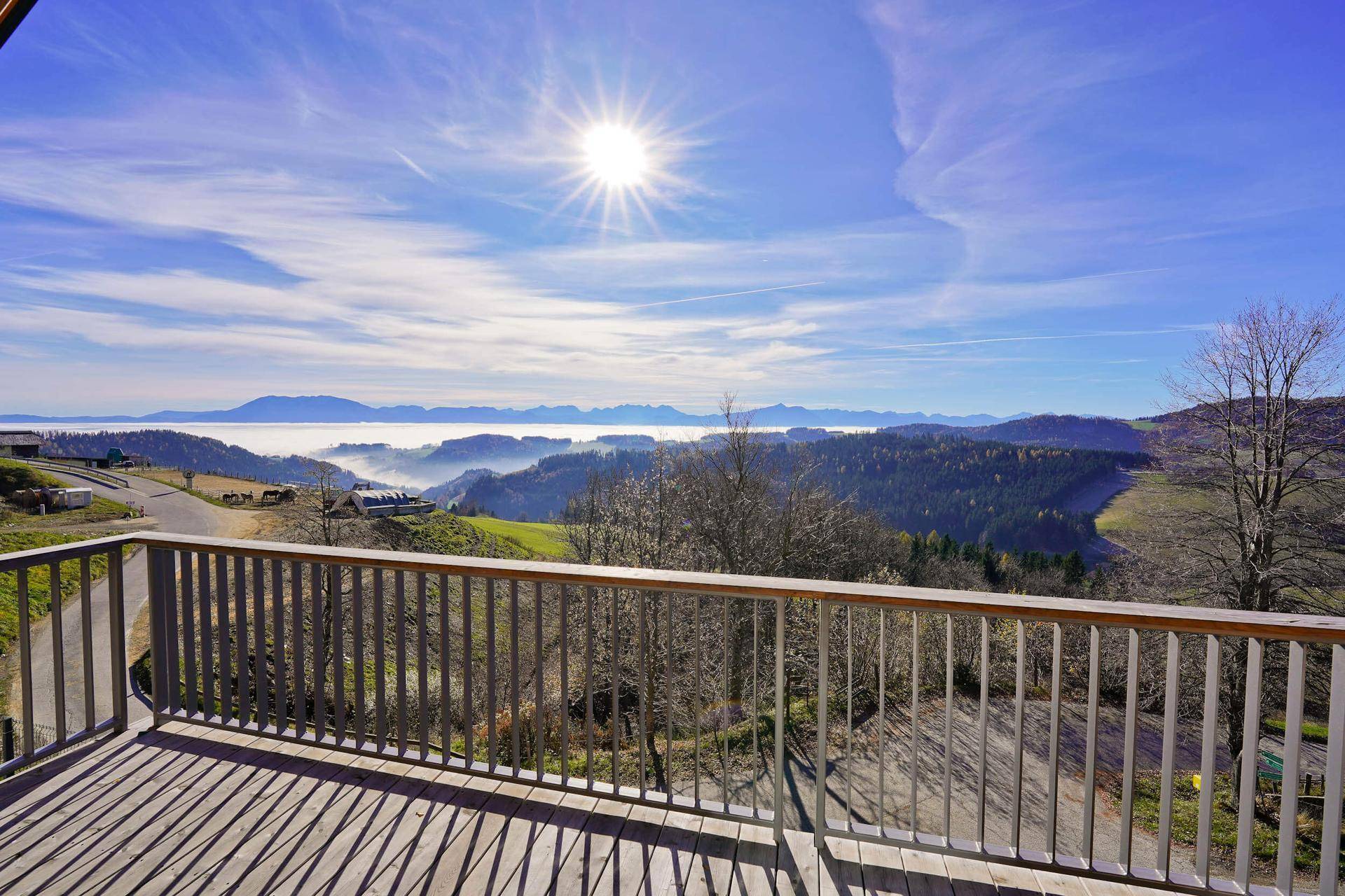 Großer Holzbalkon mit Geländer und atemberaubendem Blick über die nebelverhangene Landschaft.