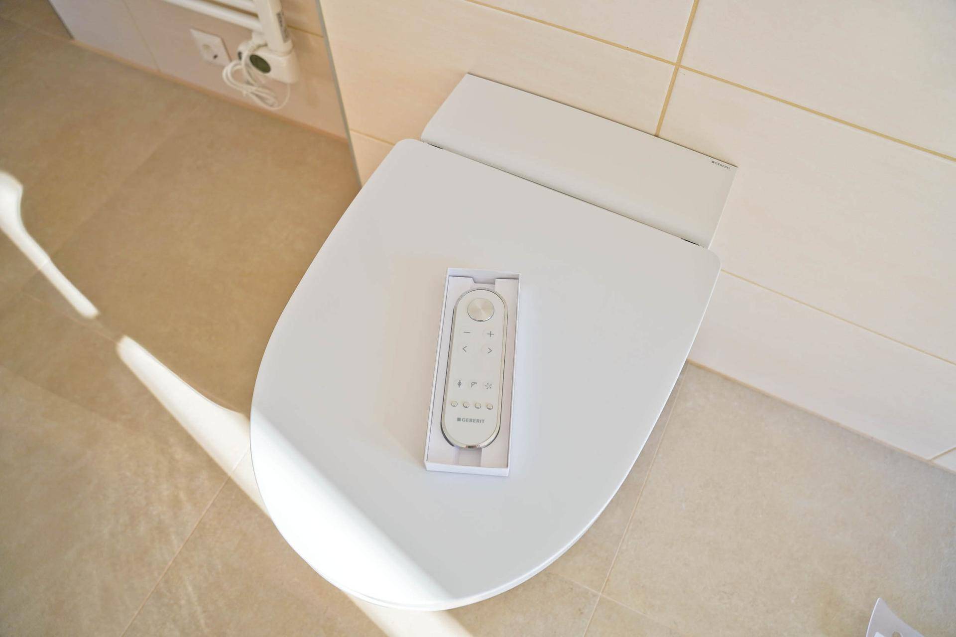 Fernbedienung für ein modernes Dusch-WC auf dem Toilettensitz in einem hellen Badezimmer.