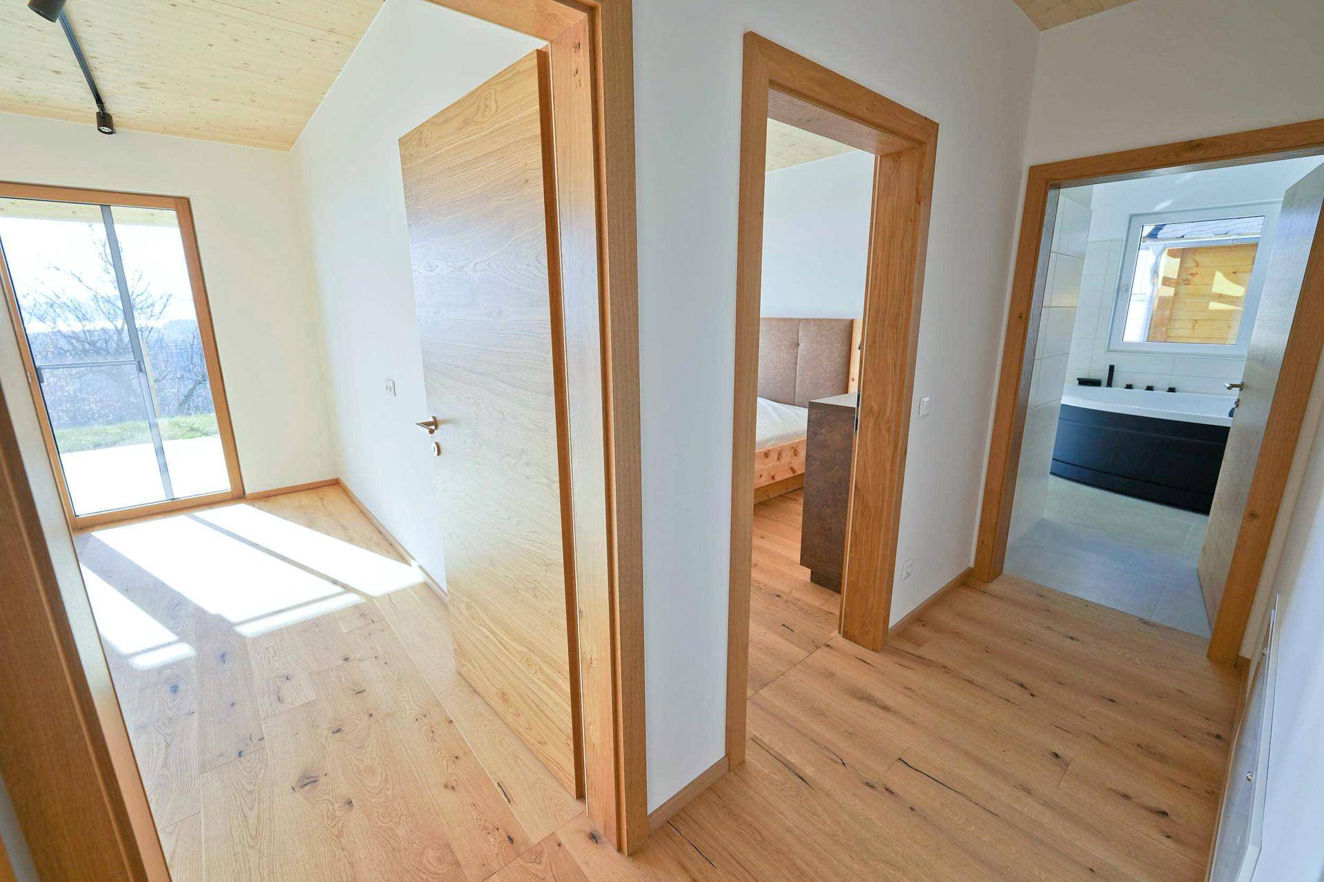 Heller Flur mit Holzboden, der zu verschiedenen Zimmern und einem Badezimmer führt.