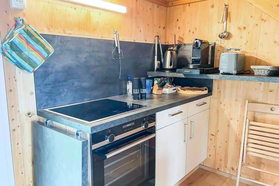 Kompakte Küchenzeile mit Kochfeld, Backofen und Kaffeemaschine, ideal für kleine Räume.