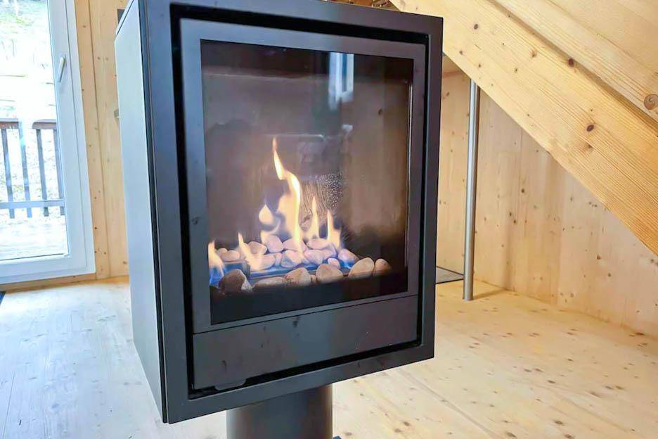 Moderner freistehender Kaminofen mit sichtbaren Flammen, der Wärme und Atmosphäre spendet.