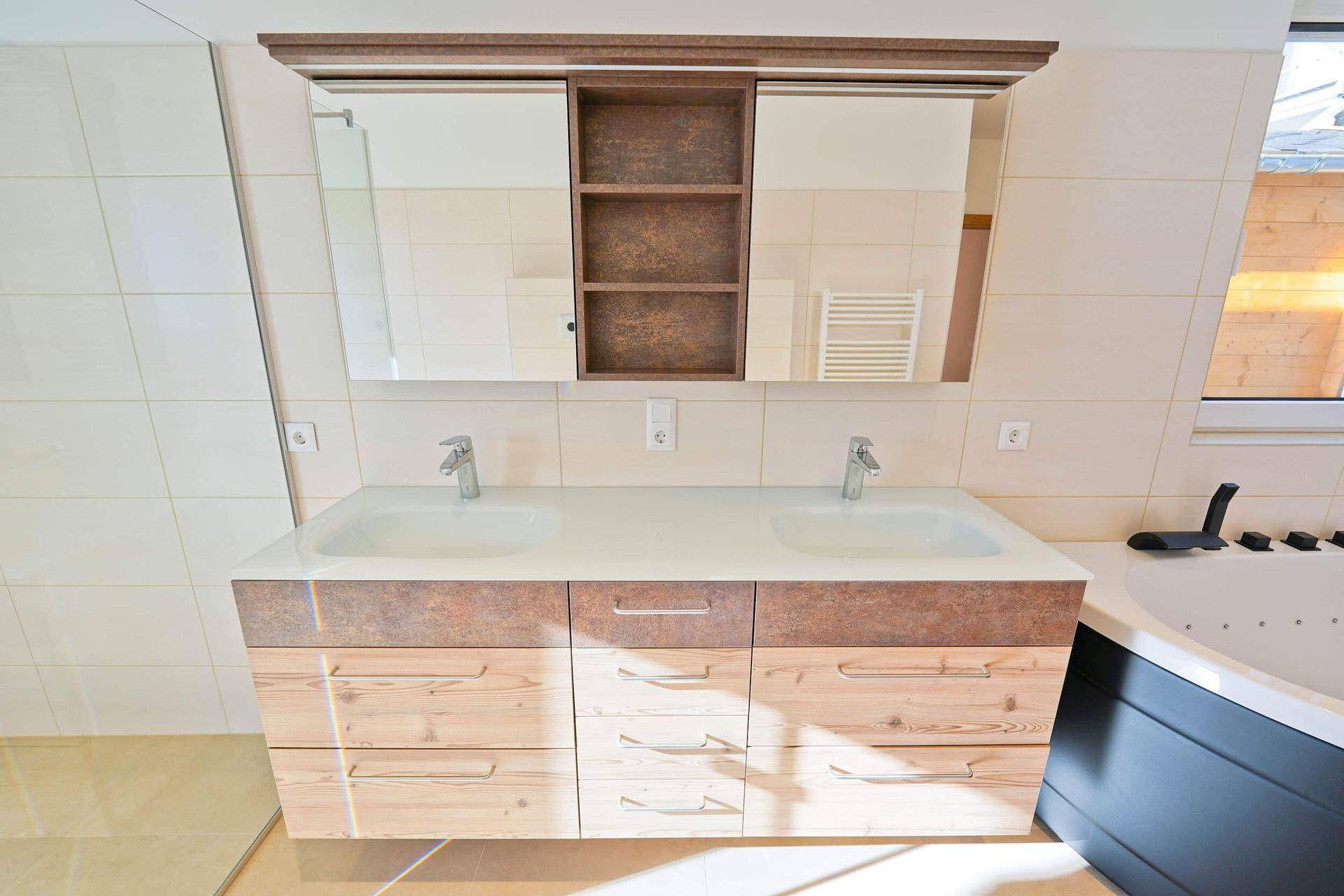 Doppelwaschbecken mit Holzunterschrank und Spiegelschrank in einem hellen Badezimmer.