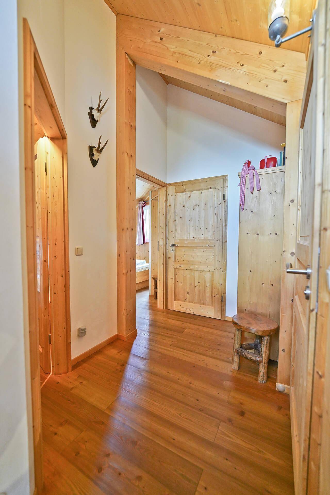 Heller Flur mit Holzvertäfelung, Holzboden und traditioneller Hirschgeweih-Dekoration.