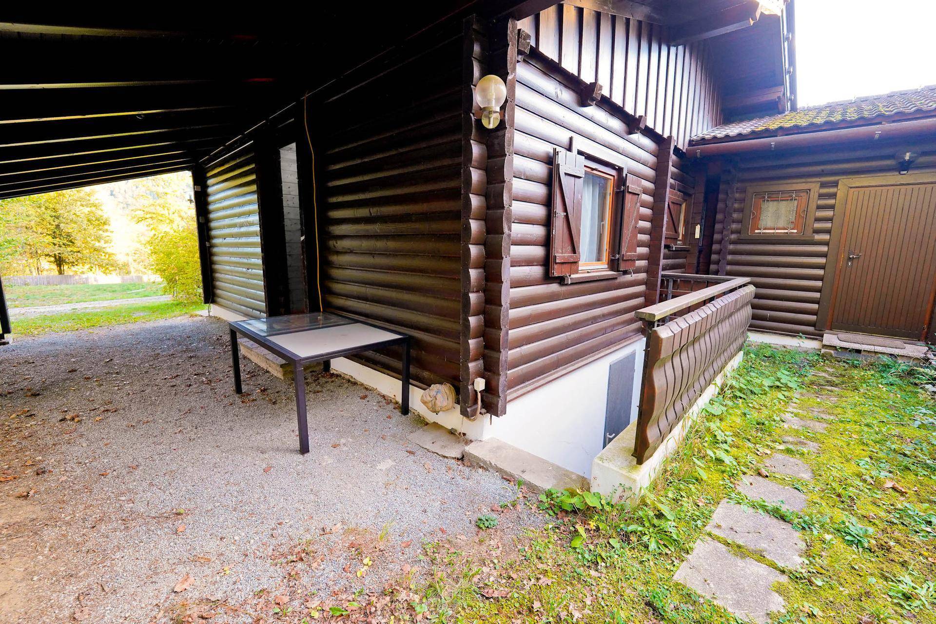 Überdachter Außenbereich neben dem Haus mit einem kleinen Tisch, ideal für geschützte Momente.