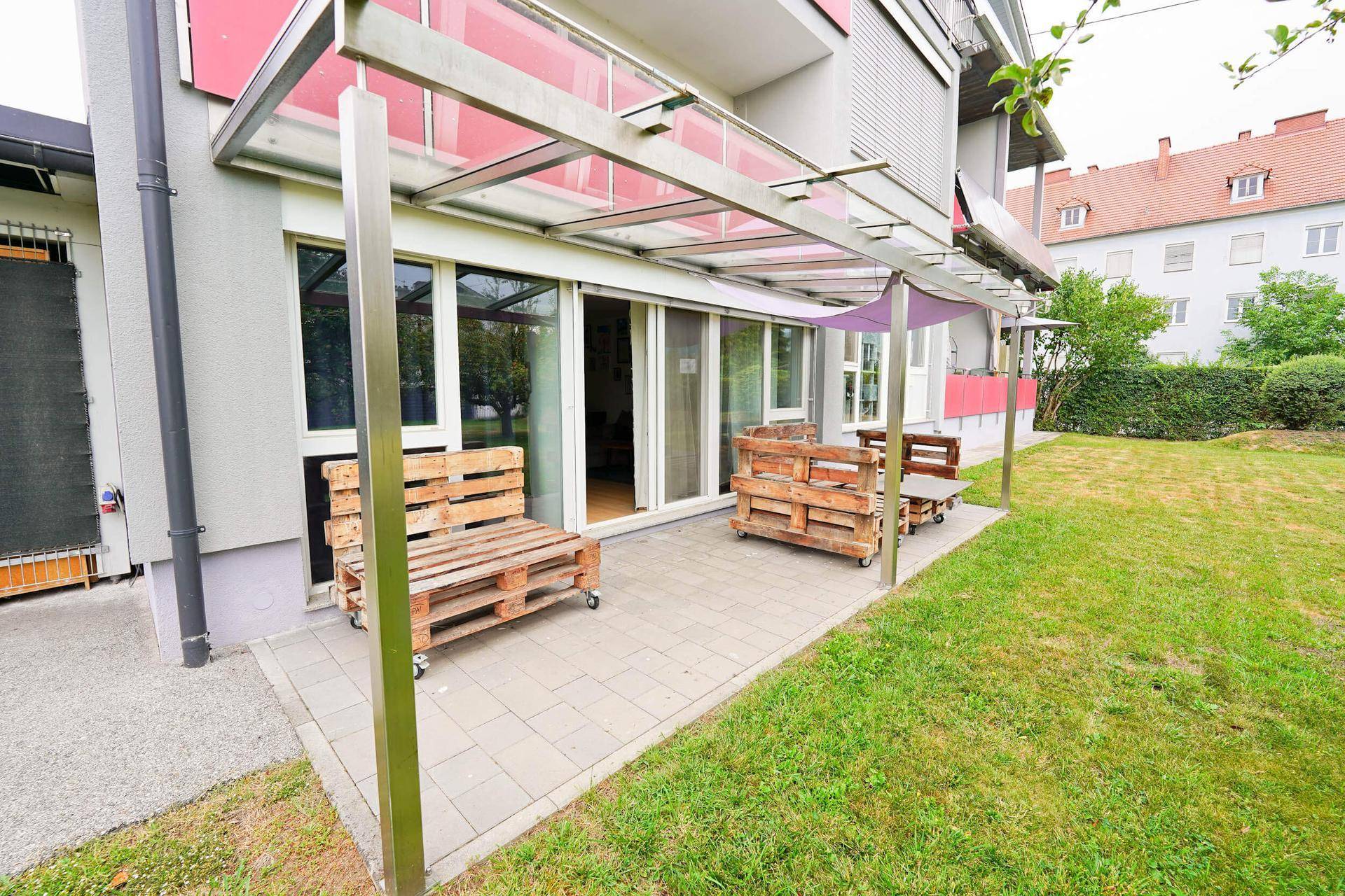 Gemütliche Terrasse mit selbstgebauten Palettenmöbeln und einer Überdachung im Gartenbereich.