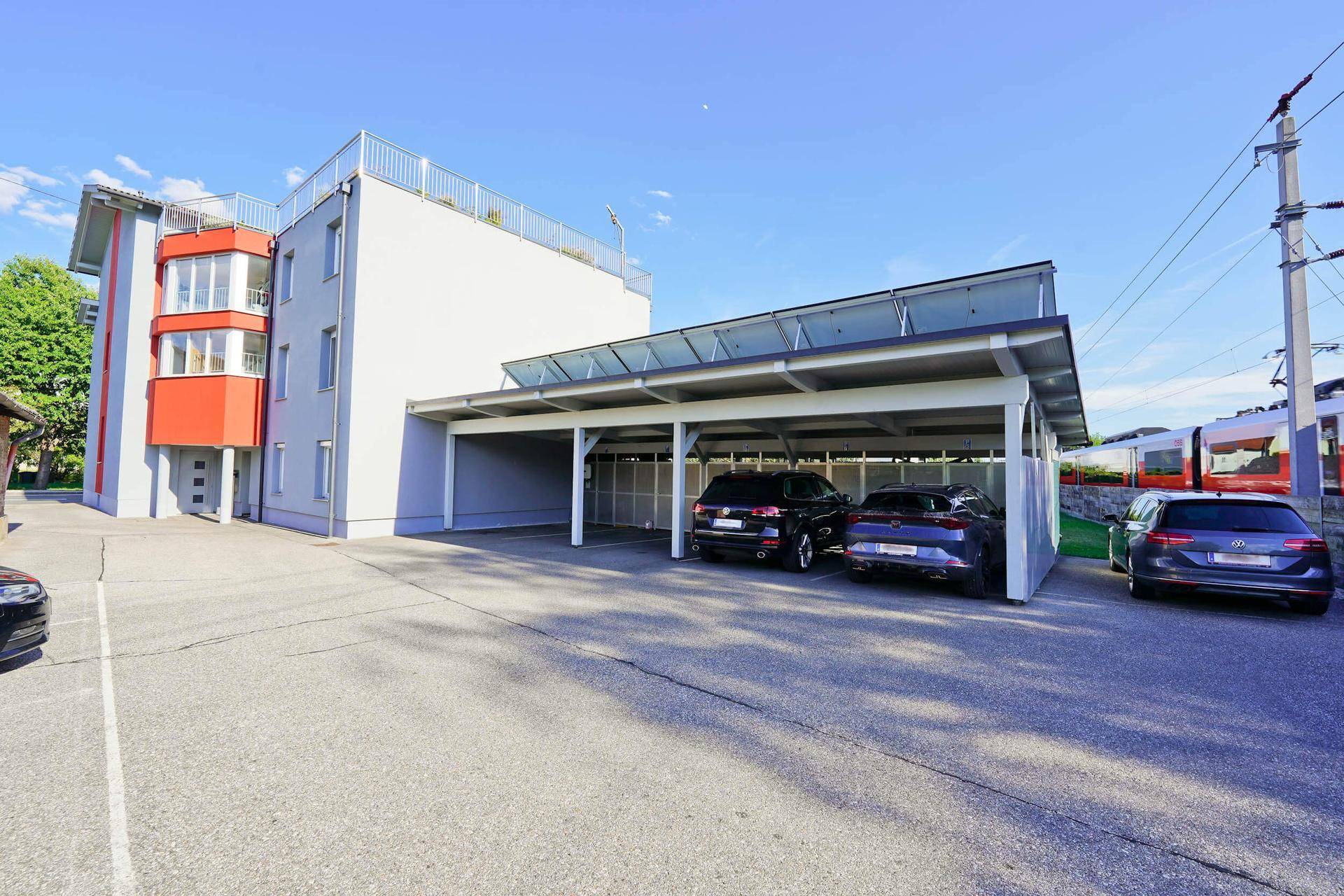 Geräumiger Parkplatz mit überdachtem Carport neben dem modernen Wohngebäude.
