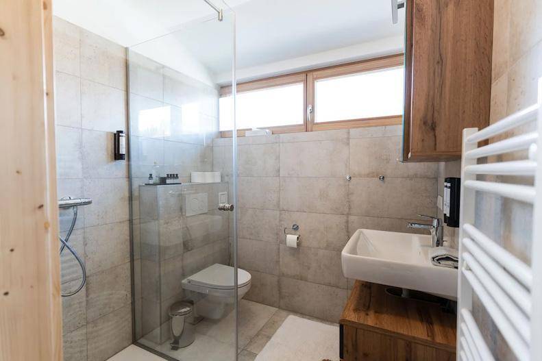 Helles Badezimmer mit Dusche, Waschbecken und Fenster.