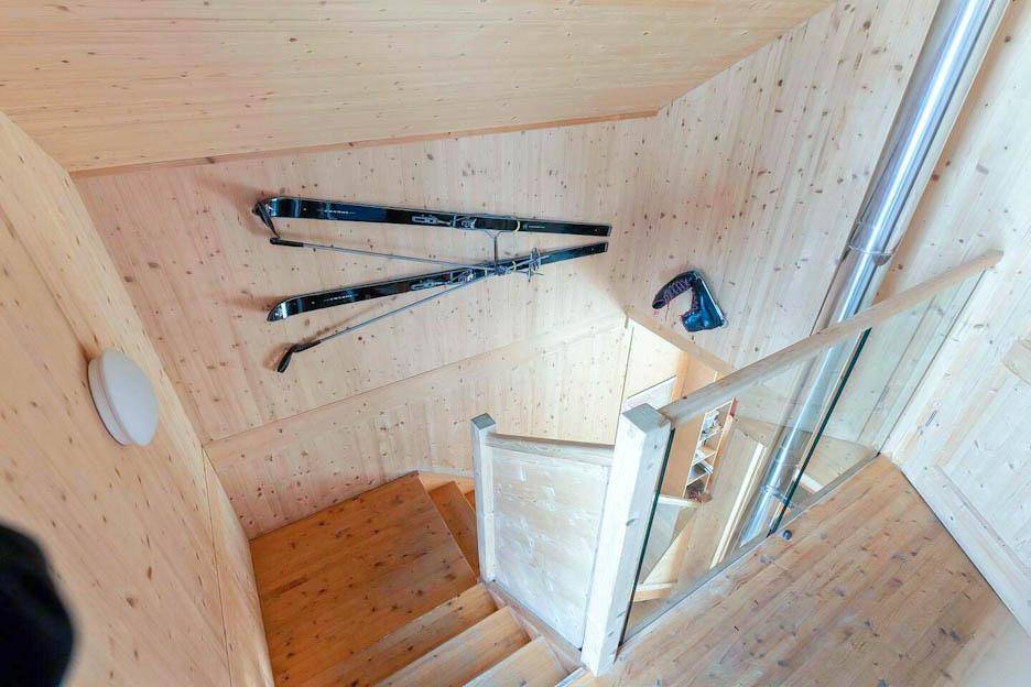 Holztreppe mit Glasgeländer und Wanddekoration, die Skier zeigt.