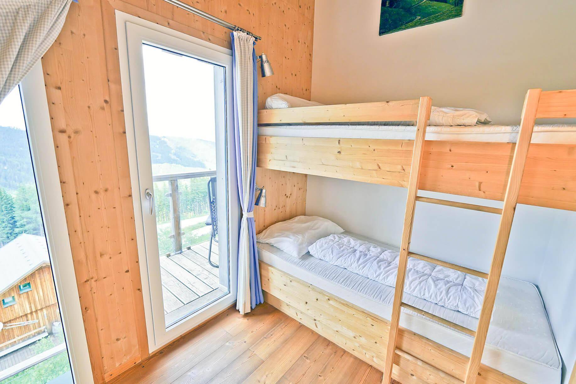 Schlafzimmer mit Etagenbett und direktem Zugang zu einem kleinen Balkon.