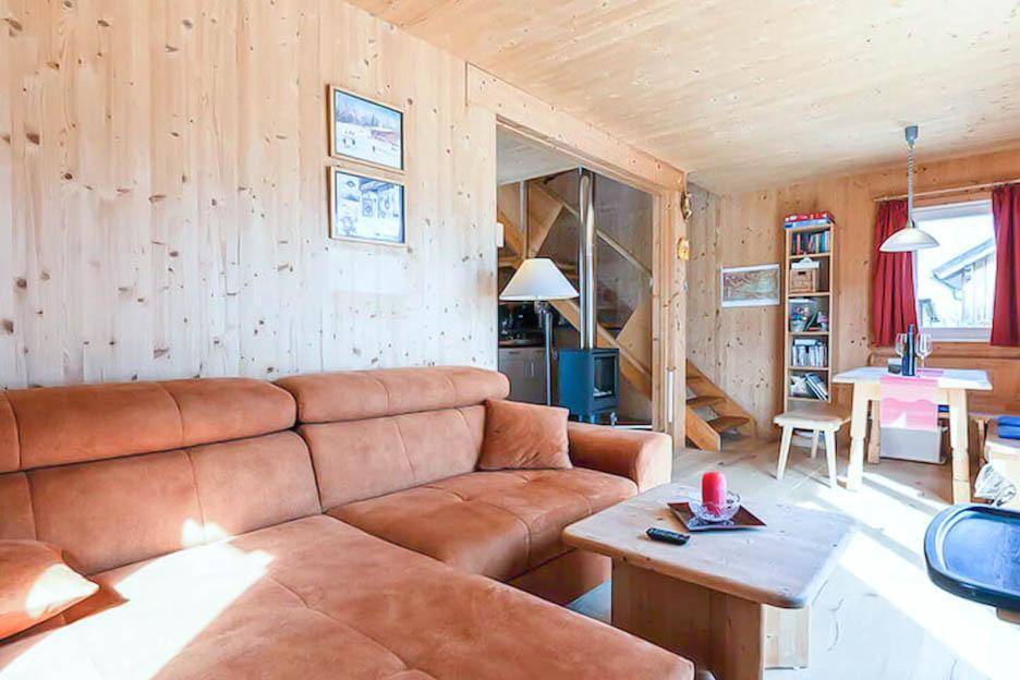 Gemütlicher Wohnbereich mit Ecksofa, Holzwänden und Esstisch, ideal zum Entspannen.