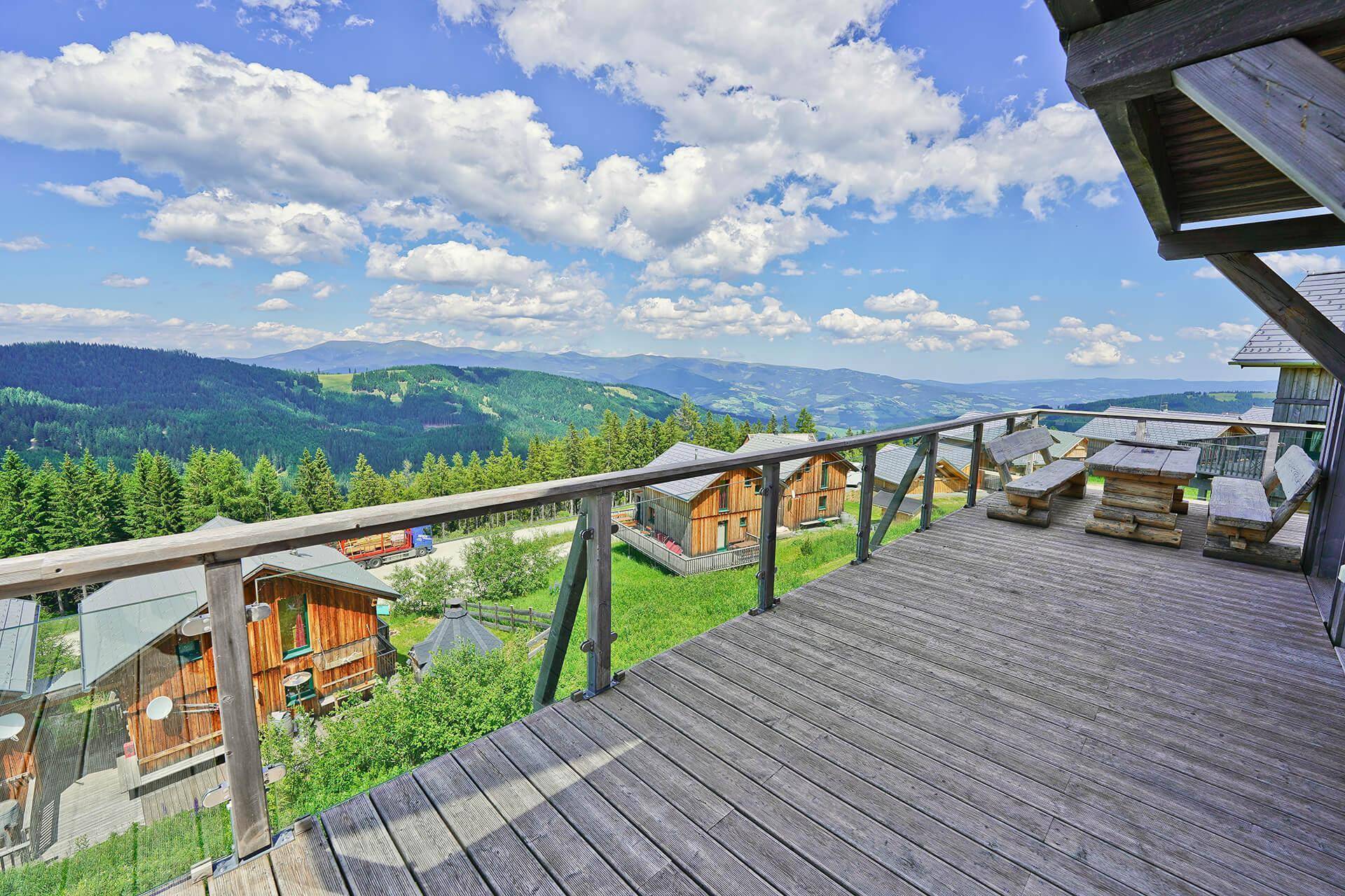 Geräumige Holzterrasse mit Sitzgelegenheiten und weitem Blick über die Berglandschaft.