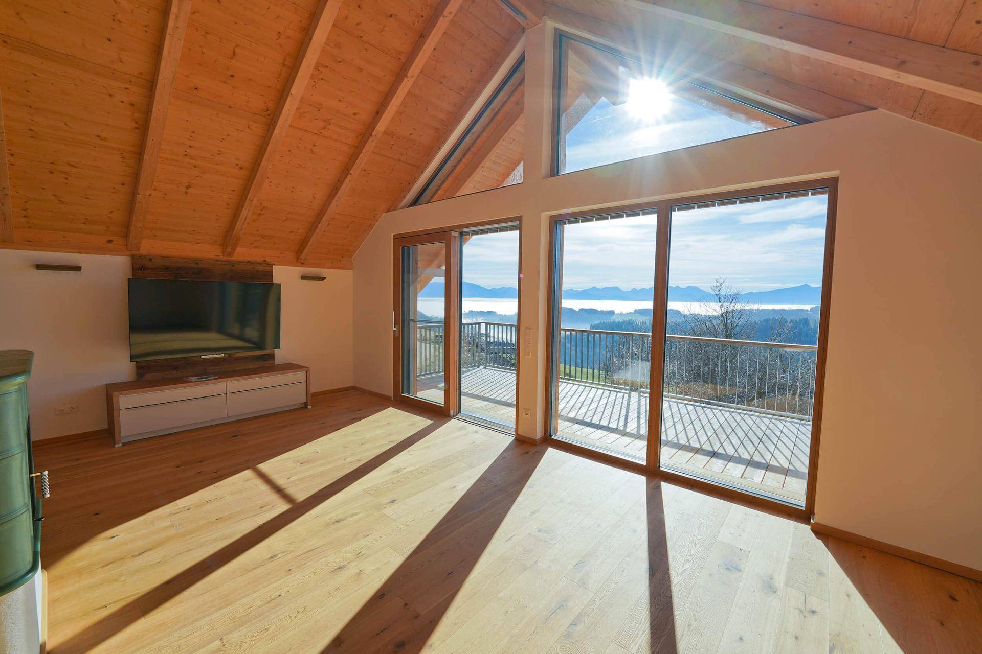 Lichtdurchfluteter Wohnbereich mit Holzboden, Dachschrägen und Panoramafenstern mit Weitblick.