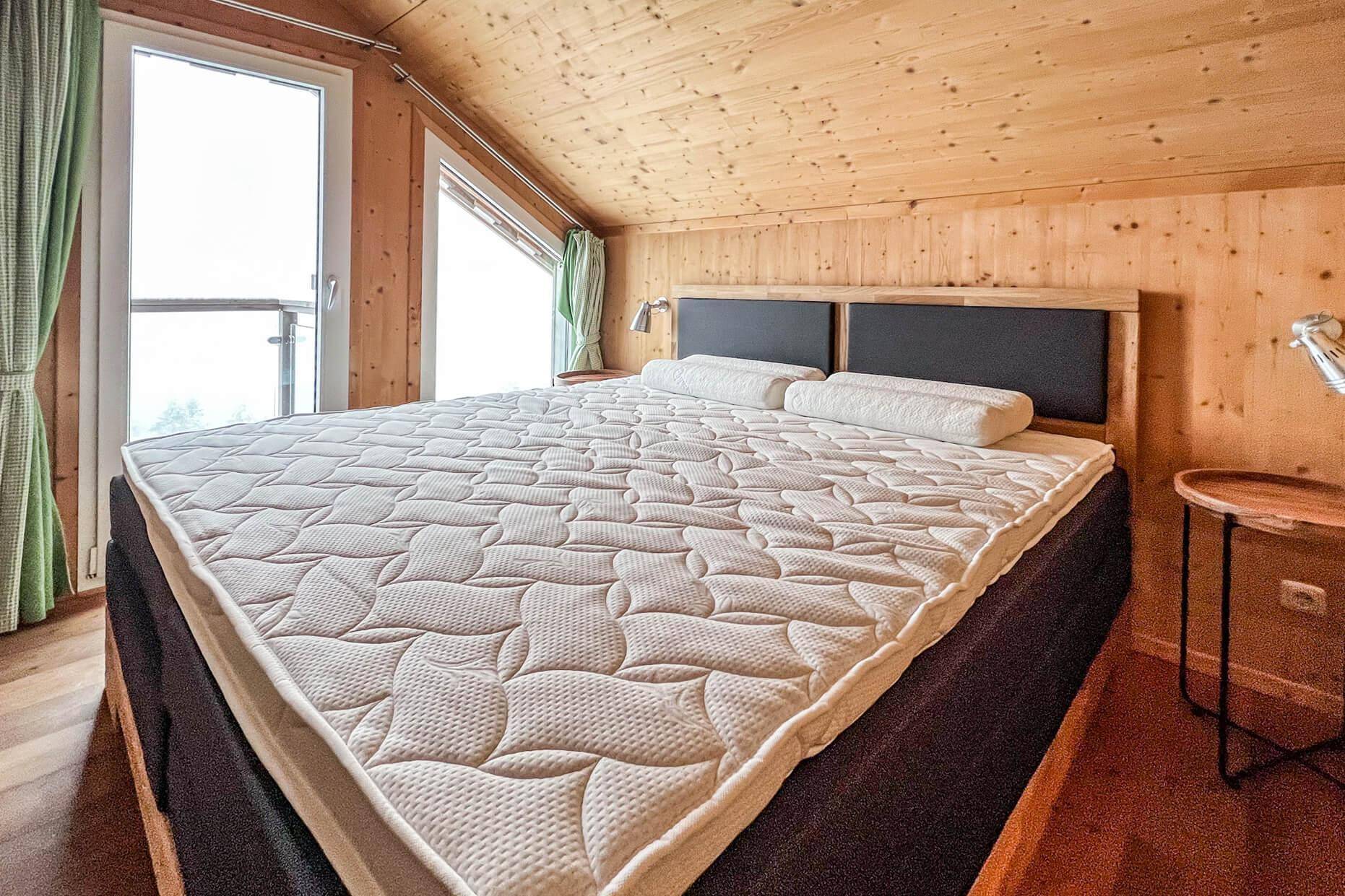 Gemütliches Schlafzimmer im Dachgeschoss mit Doppelbett und Holzvertäfelung.