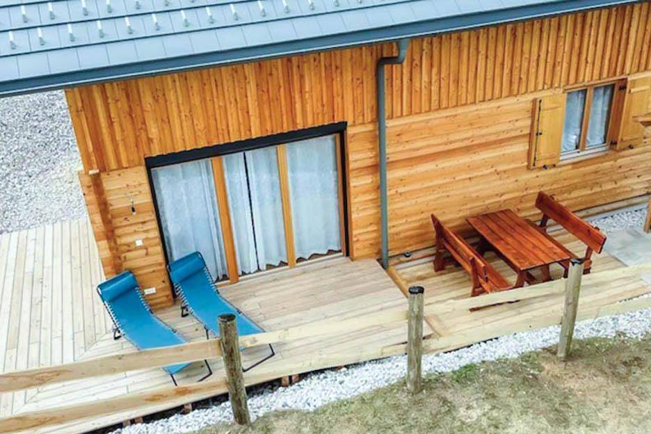 Große Holzterrasse mit Liegestühlen und Esstisch im Freien.