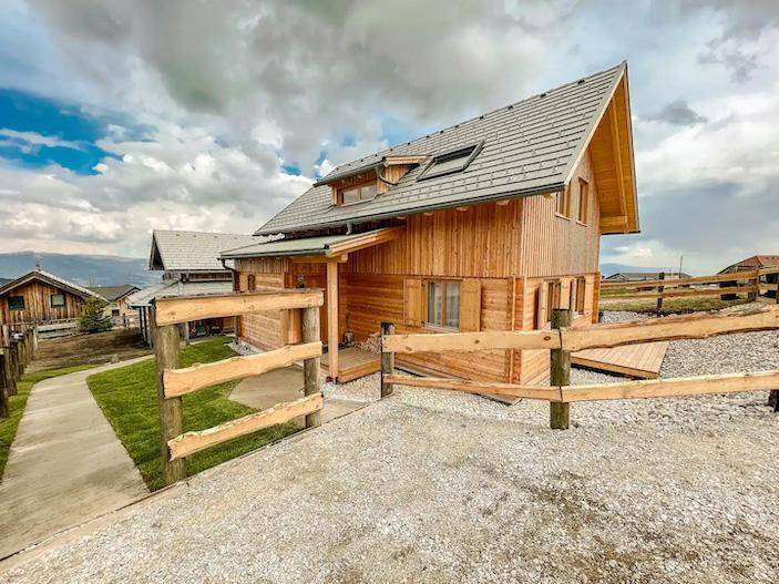 Rustikales Holzchalet mit traditionellem Zaun und Blick auf die umliegende Landschaft.