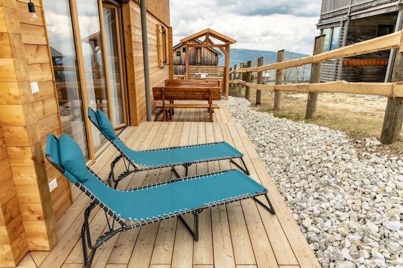 Holzterrasse mit Liegestühlen und Blick auf die Berge.