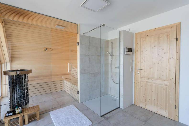 Geräumiger Wellnessbereich mit Holzsauna, Dusche und modernen Fliesen.