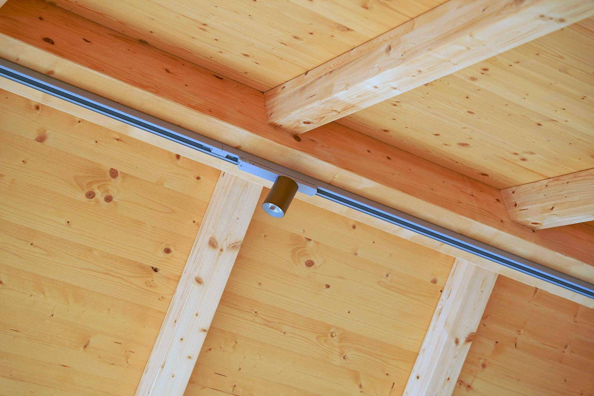 Detailaufnahme der Holzdecke mit sichtbaren Balken und moderner Beleuchtung.