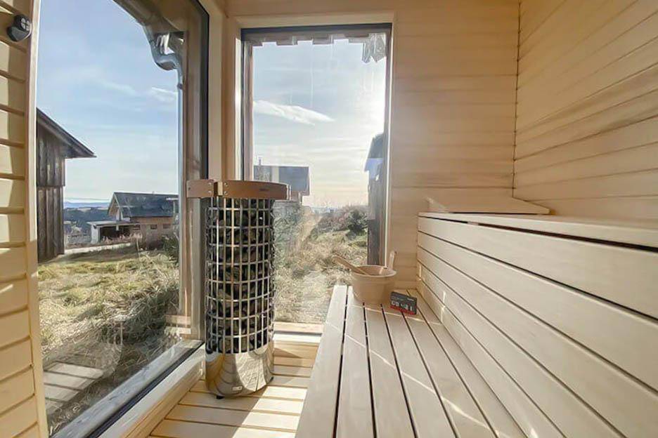 Moderne Sauna mit großen Fenstern und Panoramablick auf die umliegende Landschaft.