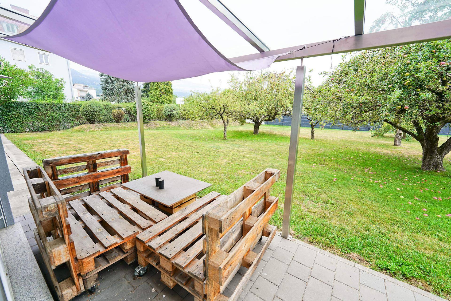 Detailansicht der Terrasse mit rustikalen Palettenmöbeln und Blick in den grünen Garten.