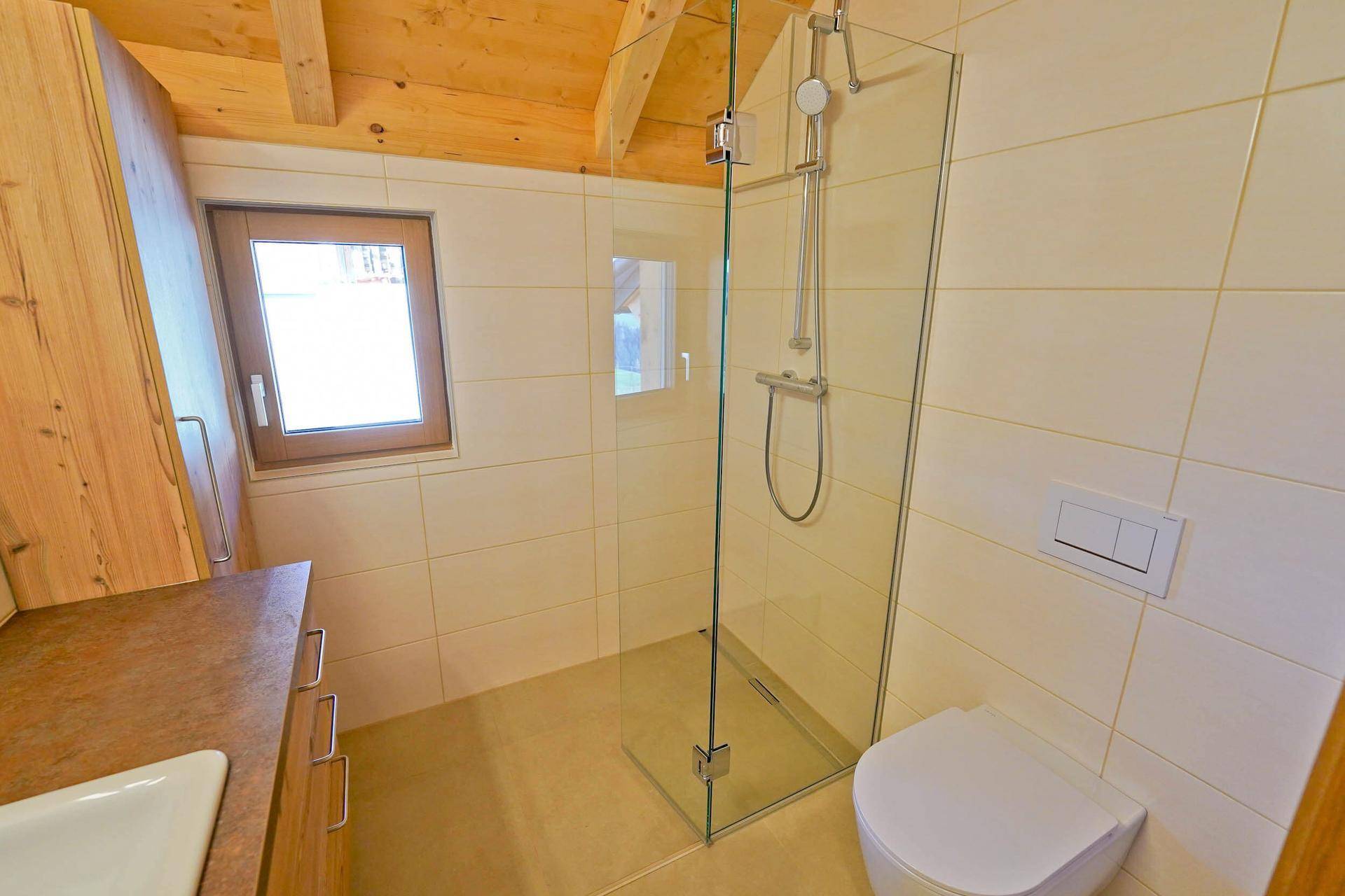 Modernes Badezimmer mit ebenerdiger Dusche, Wand-WC und Fenster unter der Dachschräge.