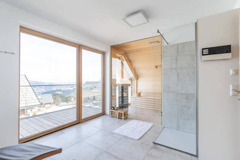 Wellnessbereich mit Sauna, Dusche und großen Fenstern mit Bergblick.