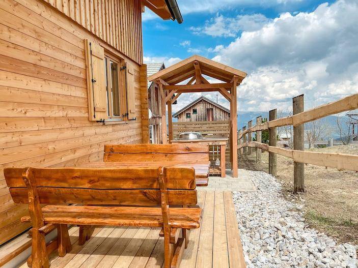 Rustikale Holzterrasse mit Sitzbänken und Grillplatz im Freien.