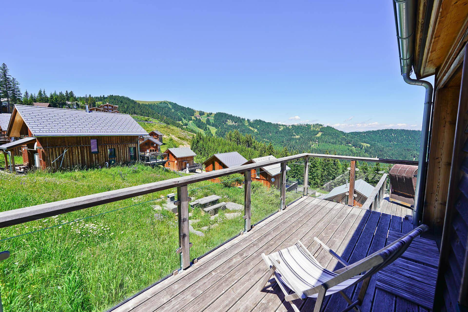 Kleiner Balkon mit Liegestuhl und Blick auf die grüne Berglandschaft.