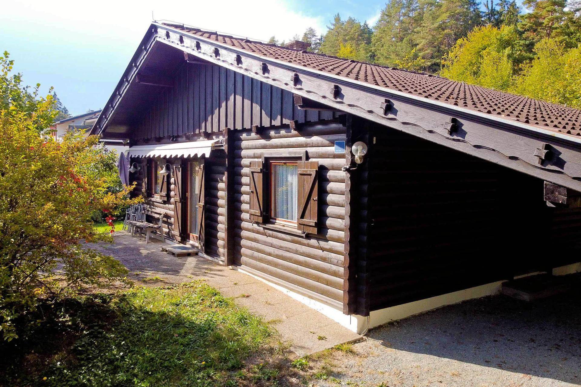 Seitenansicht des rustikalen Holzchalets mit Blockhaus-Optik und einem kleinen gepflasterten Weg.