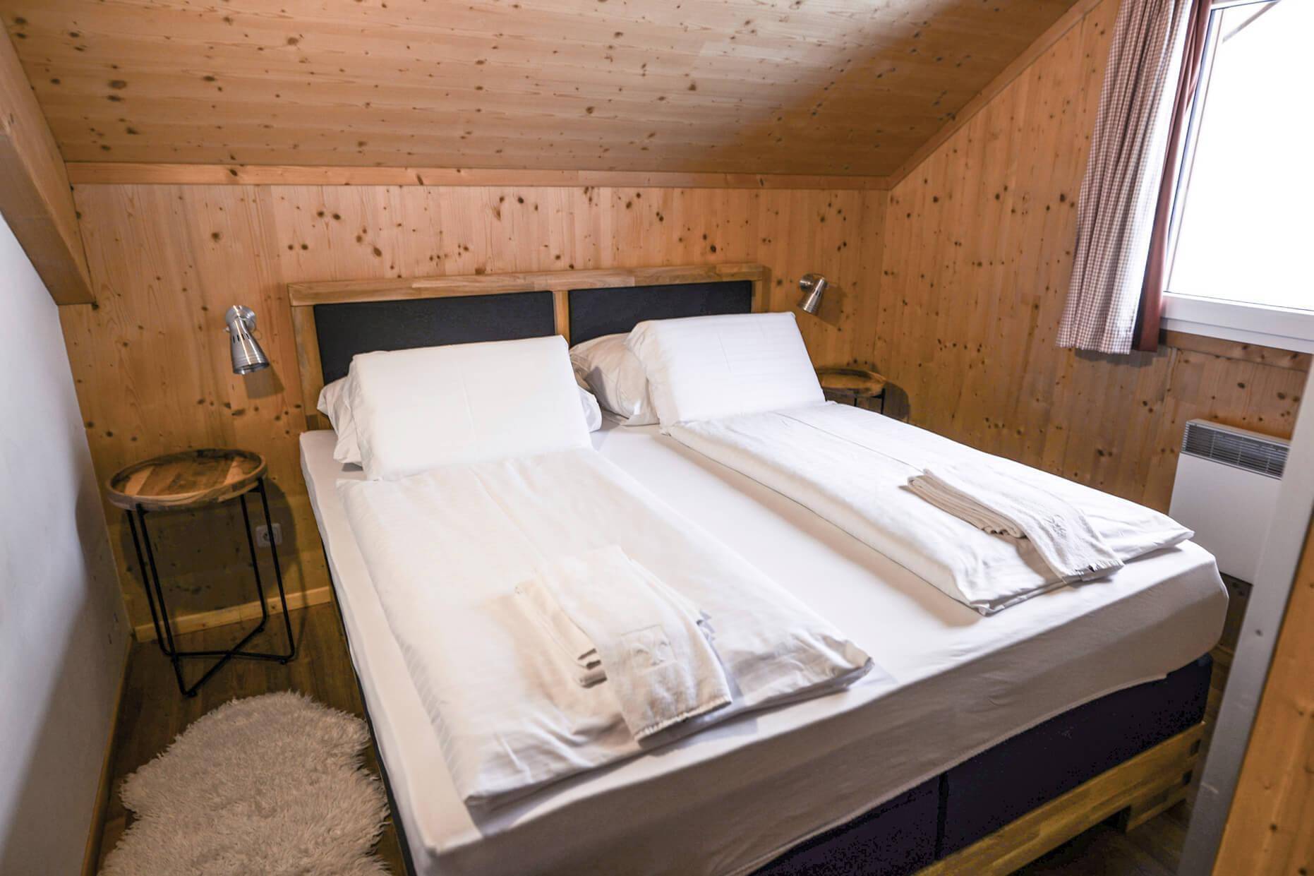 Schlafzimmer im Dachgeschoss mit Doppelbett, Holzwänden und schrägen Decken.