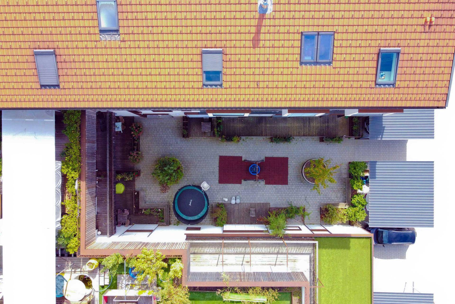 Innenhof mit Spielbereich, Trampolin und gepflasterten Wegen, umgeben von Gebäuden.