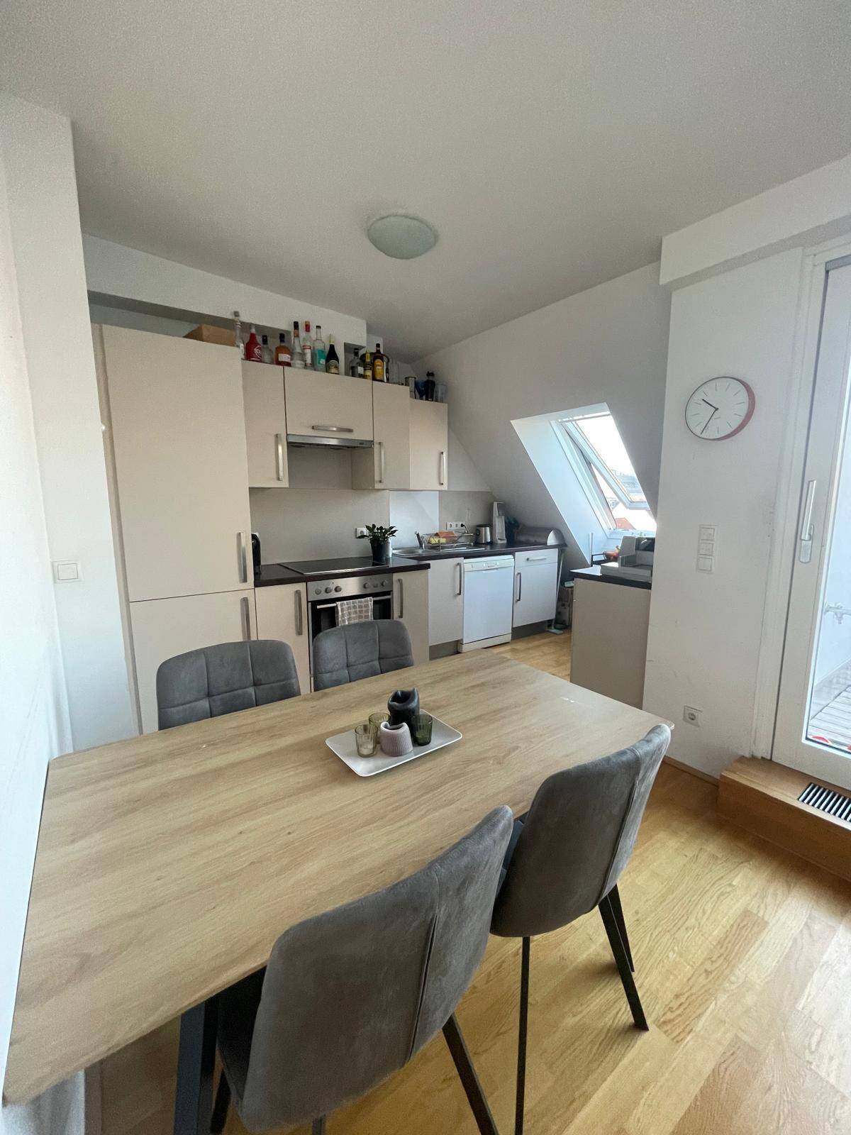 Moderne Einbauküche mit Essbereich, Holzboden und Dachfenster, hell und funktional.