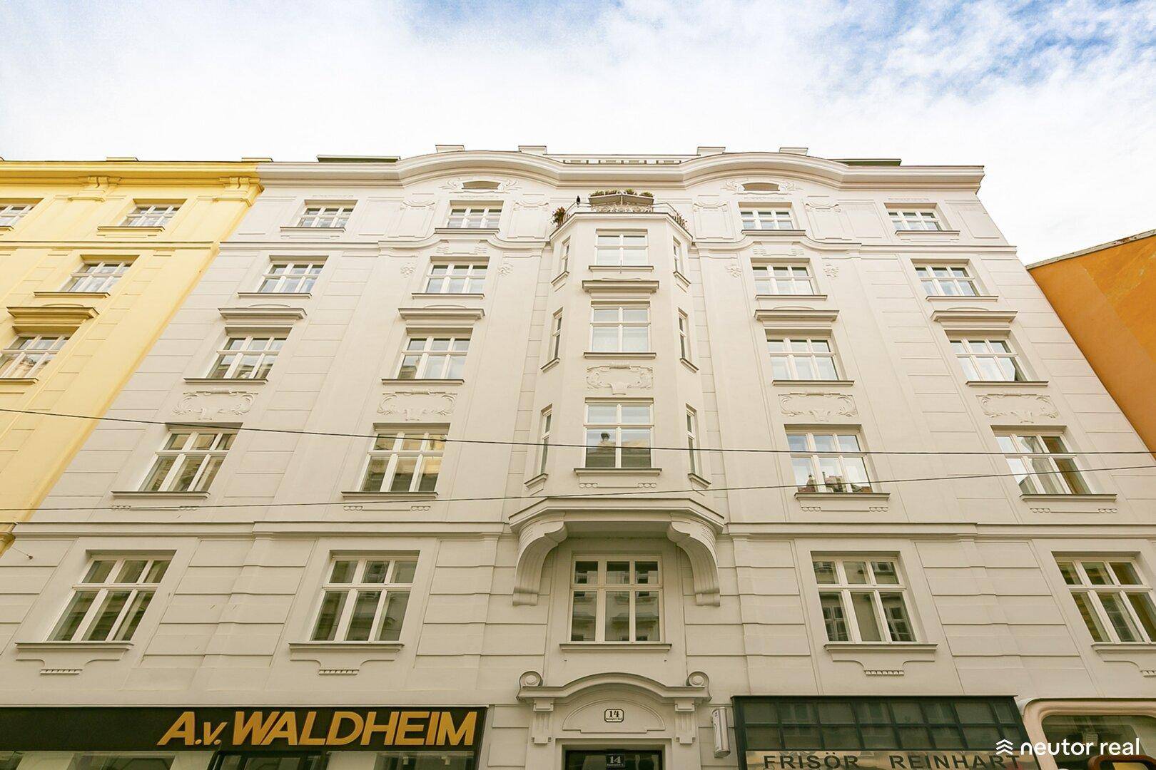 Klassische Fassade eines eleganten Mehrfamilienhauses mit vielen Fenstern und einem Erker.