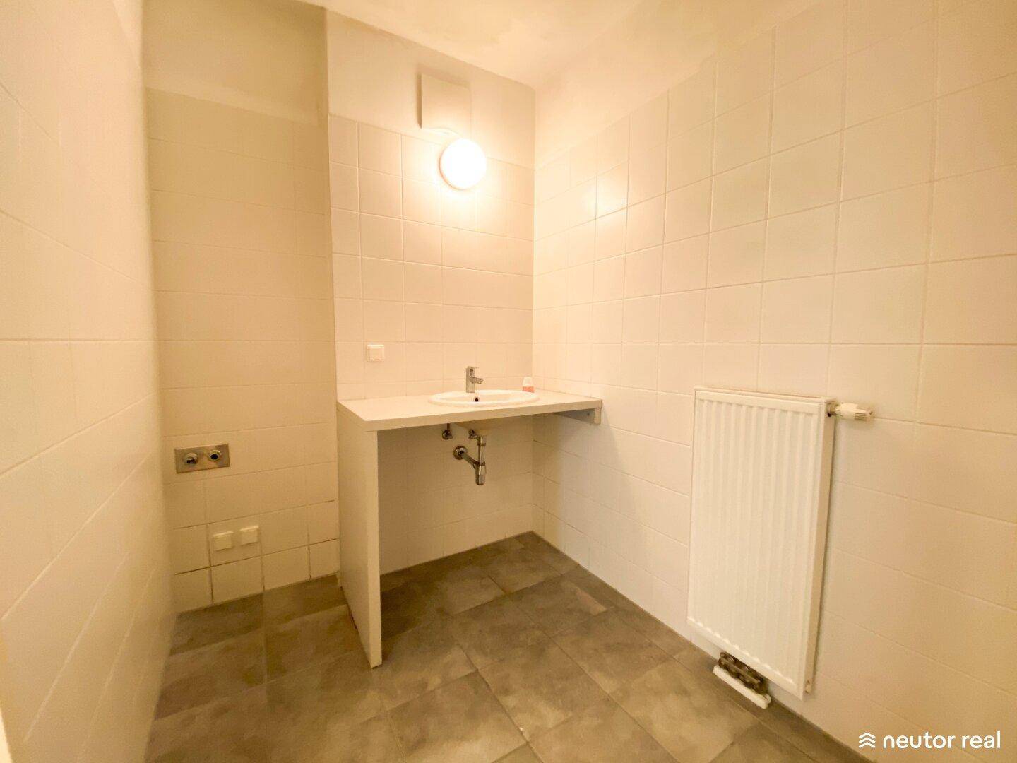 Badezimmer mit gefliesten Wänden und Boden, vorbereitet für einen Waschtisch.