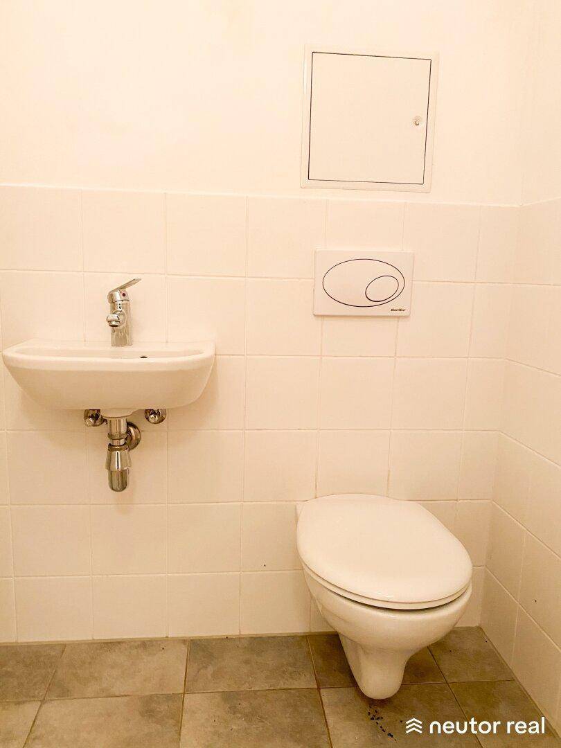 Kleines Gäste-WC mit Wand-WC und Handwaschbecken, komplett gefliest.
