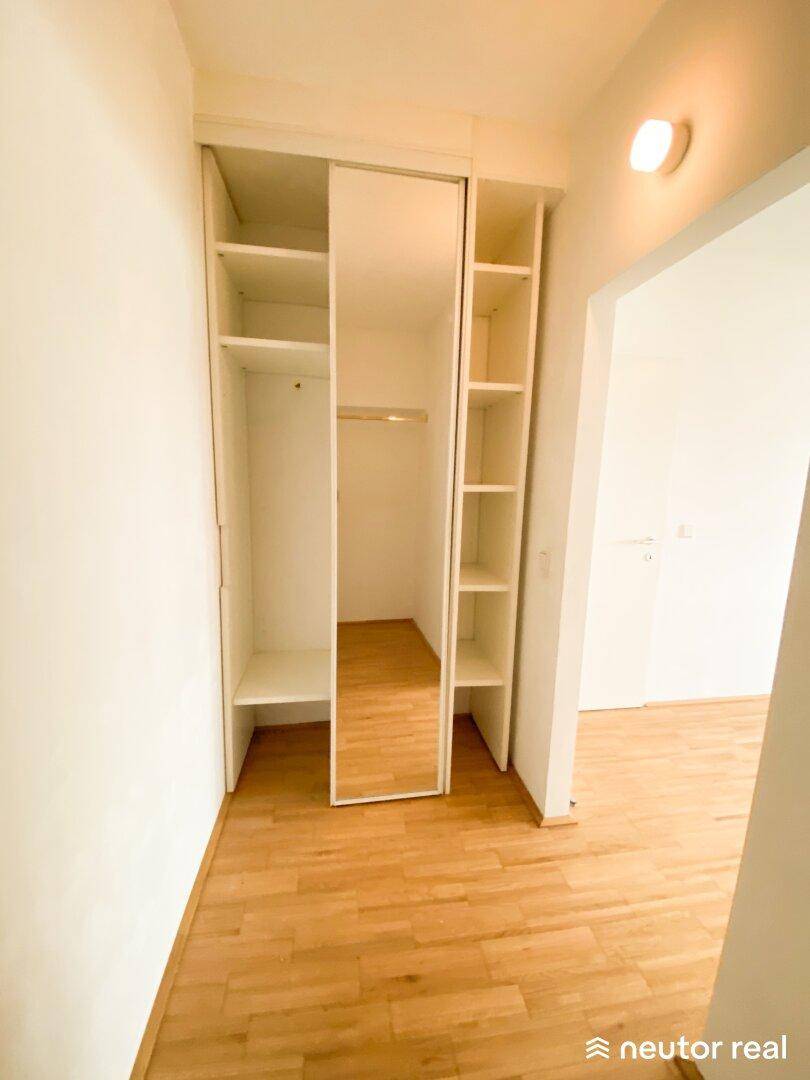 Flur mit eingebautem Kleiderschrank, Spiegeltüren und offenen Regalen.