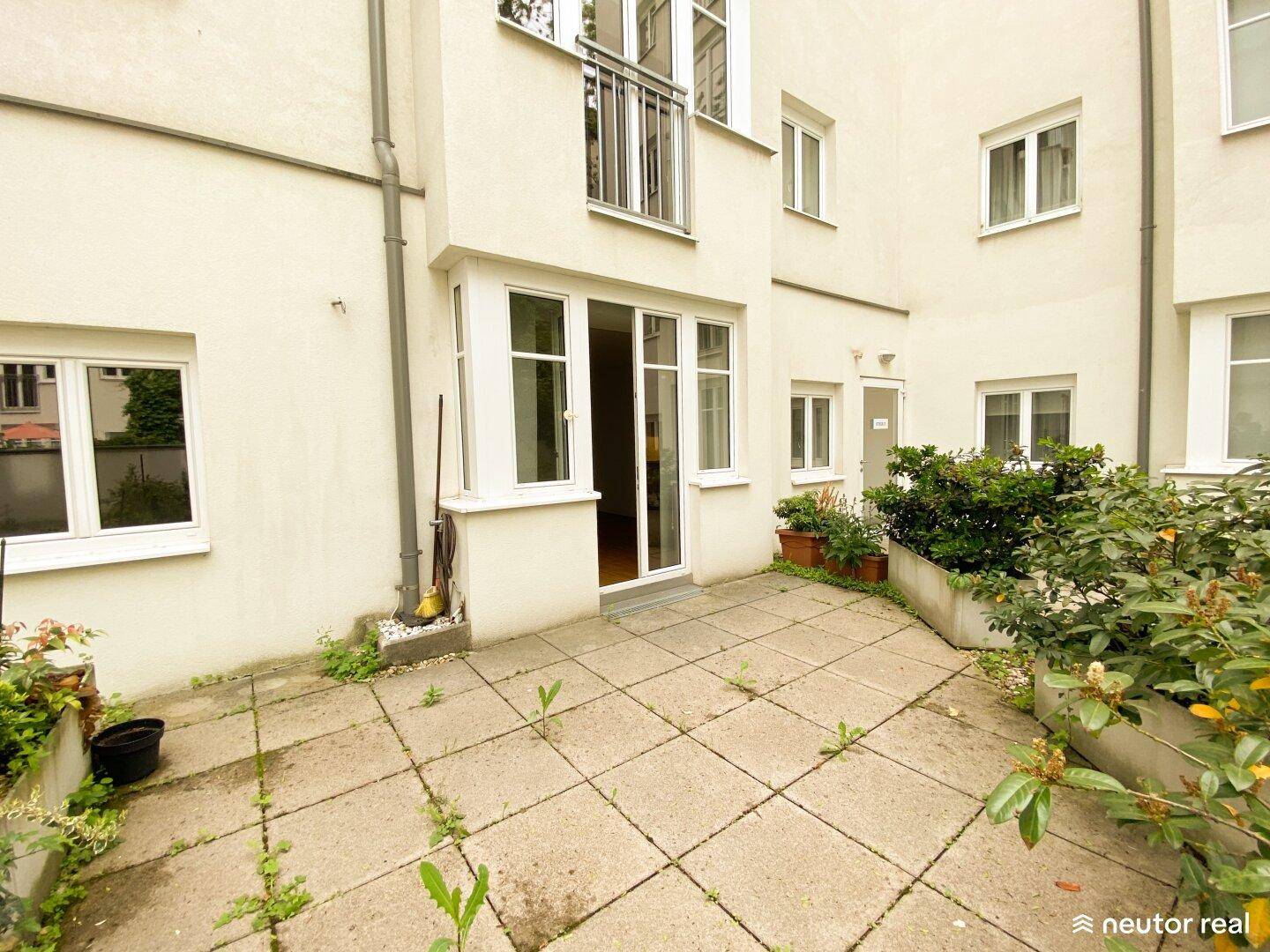 Gepflasterter Terrassenbereich mit Pflanzenkübeln und Zugang zum Gebäude.