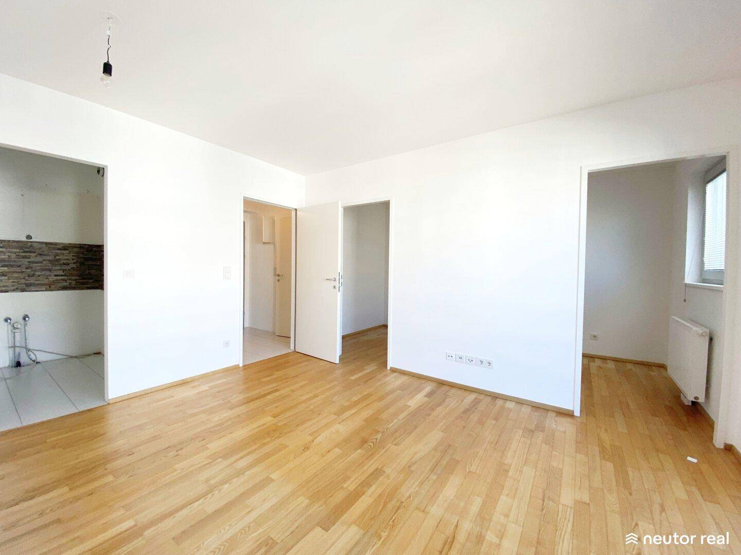Geräumiger, heller Raum mit Parkettboden und mehreren Türöffnungen, bereit zur individuellen Gestaltung.