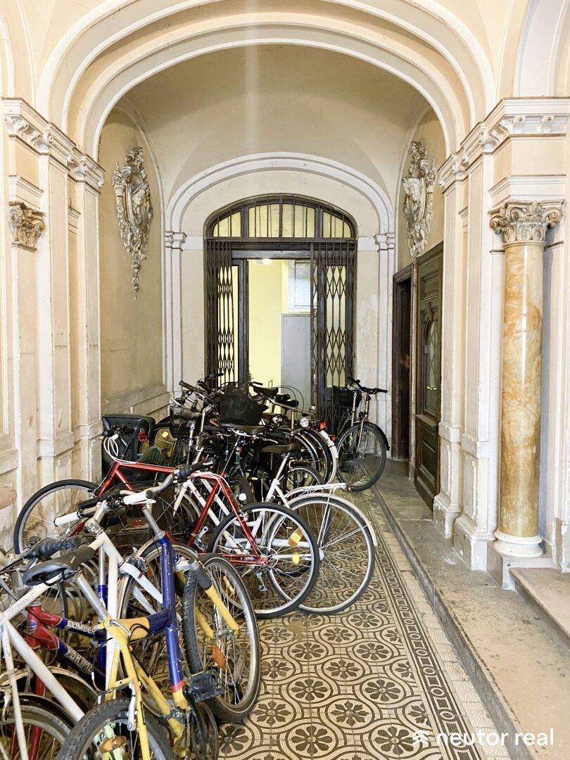 Historischer Eingangsbereich mit vielen Fahrrädern, verzierten Säulen und gemustertem Fliesenboden.