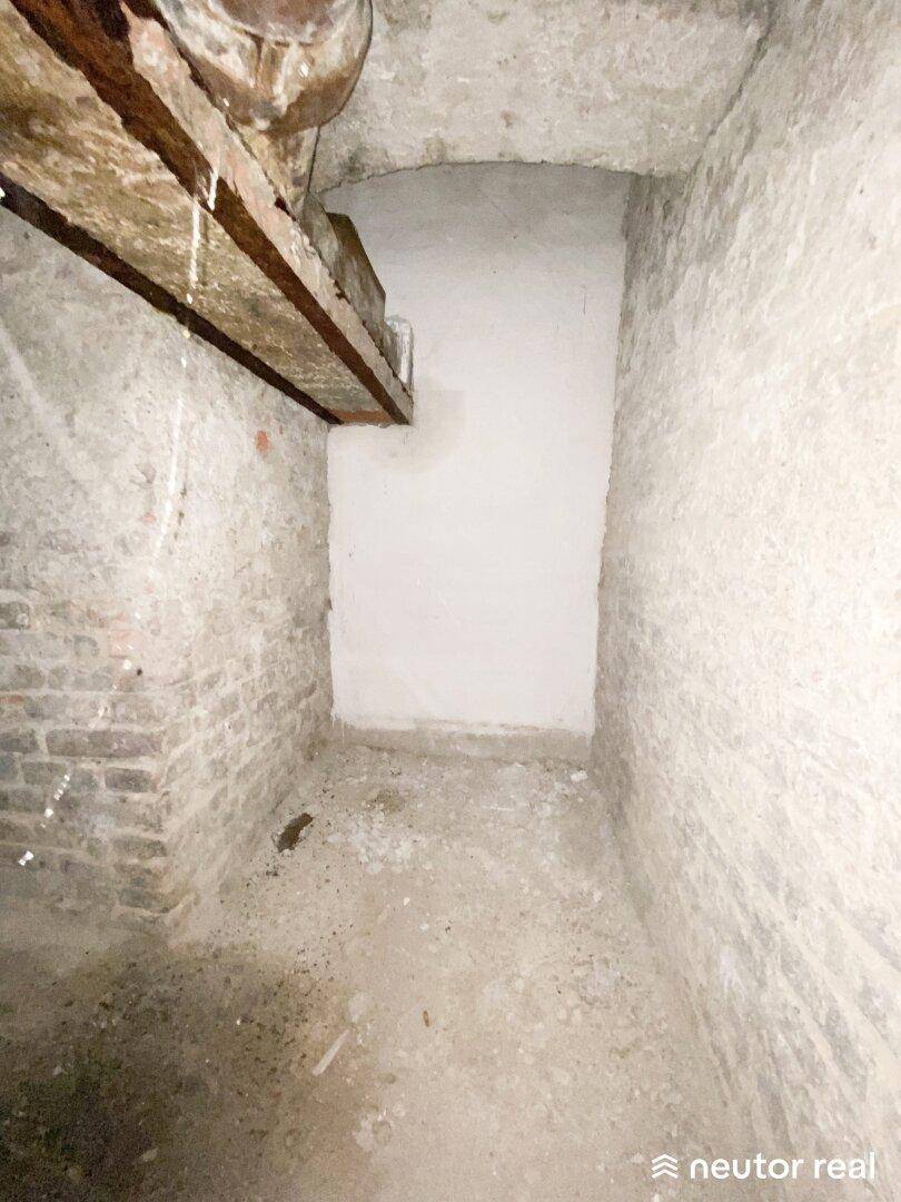 Alter Kellerraum mit unverputzten Ziegelwänden und Betonboden, in ursprünglichem Zustand.