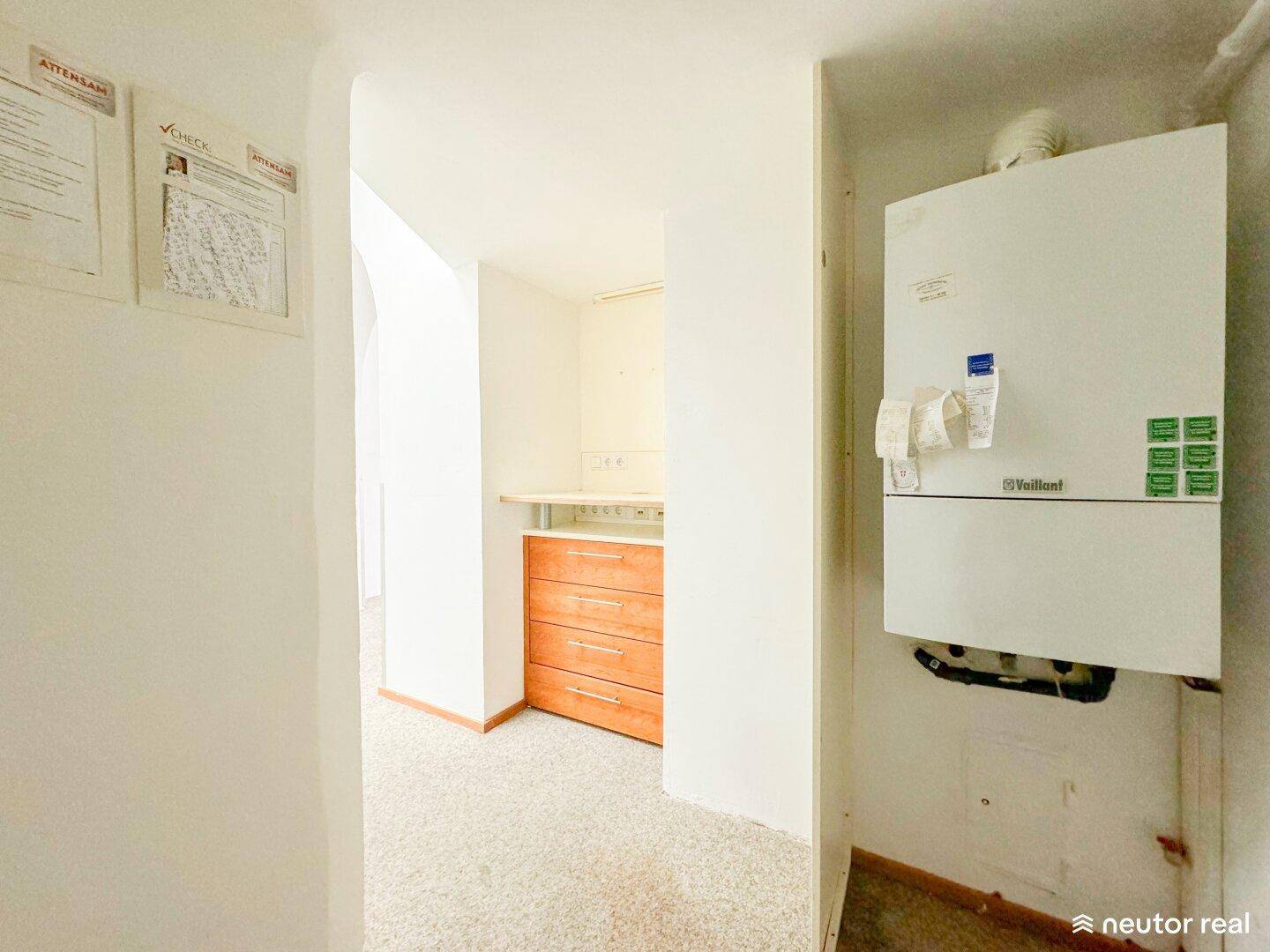 Flur mit Gastherme an der Wand und einem kleinen Bereich mit Holzschränken und Arbeitsplatte.