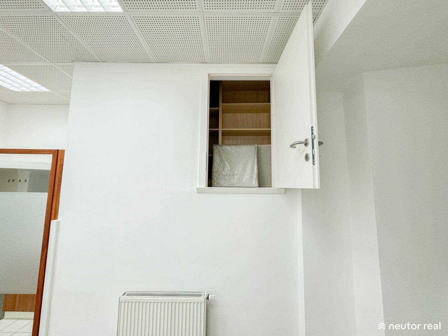 Weißer Raum mit Heizkörper und einer offenen Nische mit Regalen, ideal für Lagerung.