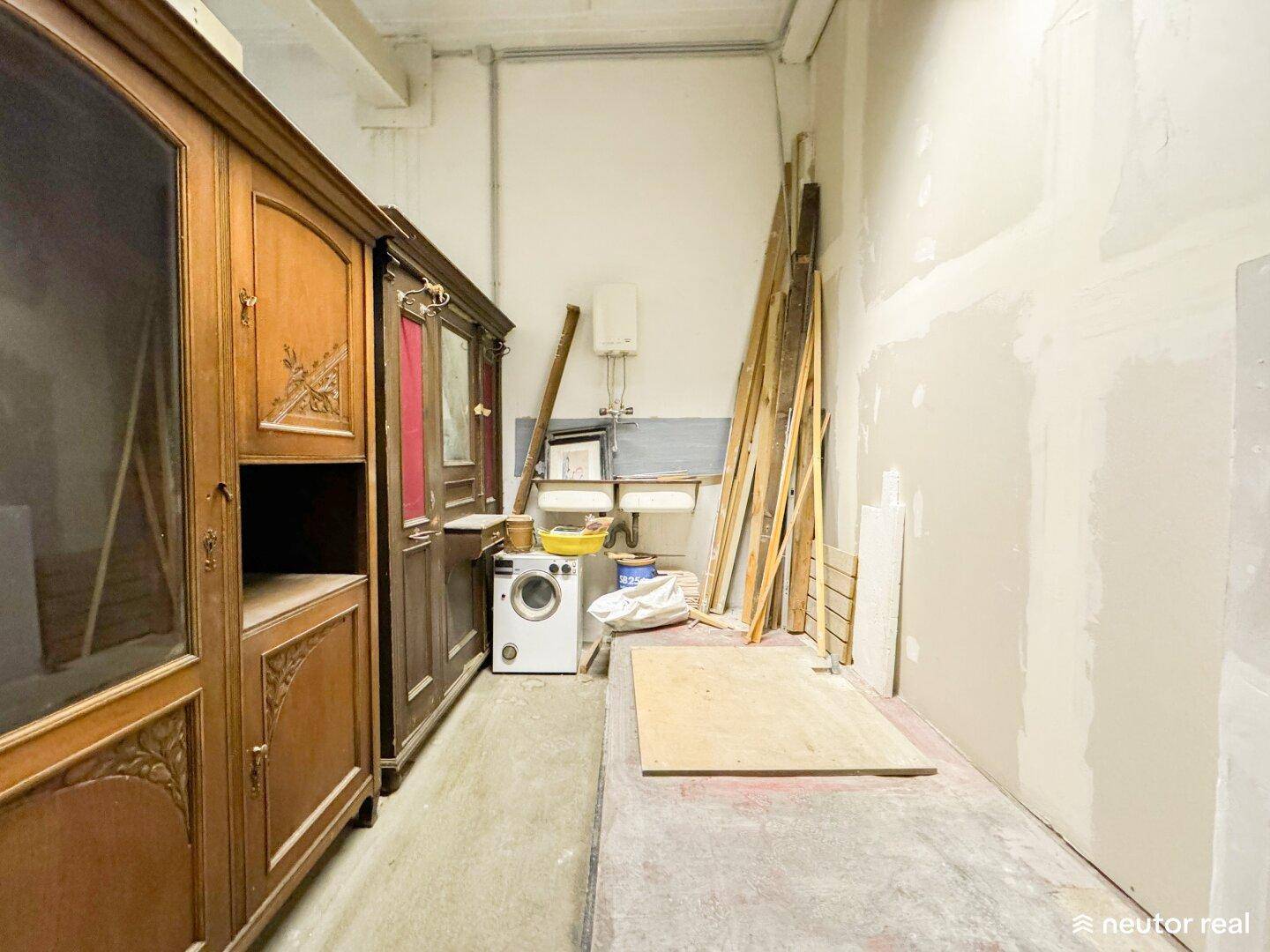 Kellerraum mit alten Holzschränken, Waschmaschine und Baumaterialien, in Renovierungszustand.