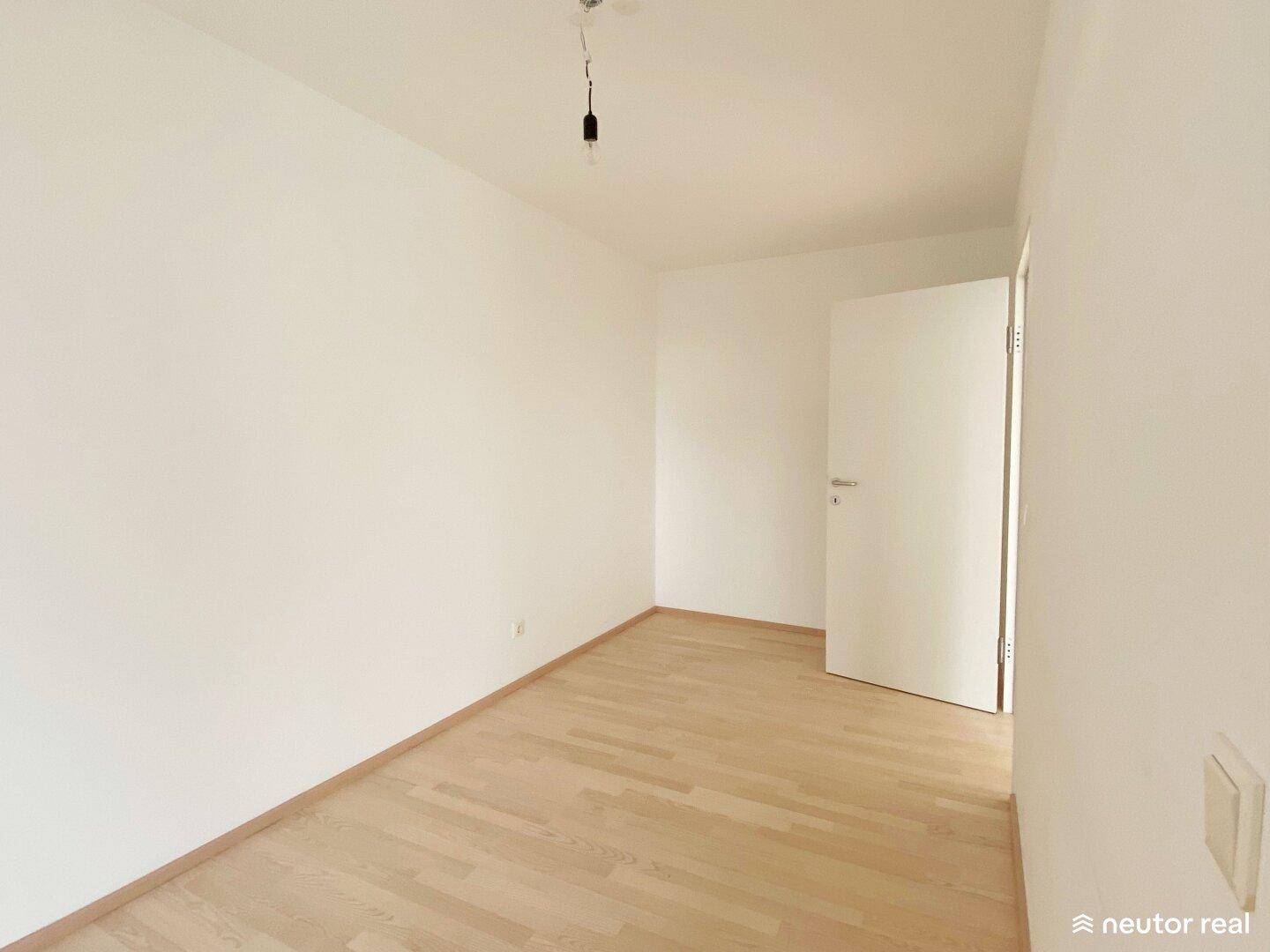 Ruhiges Schlafzimmer mit hellem Parkettboden und weißen Wänden, bereit zum Einrichten.