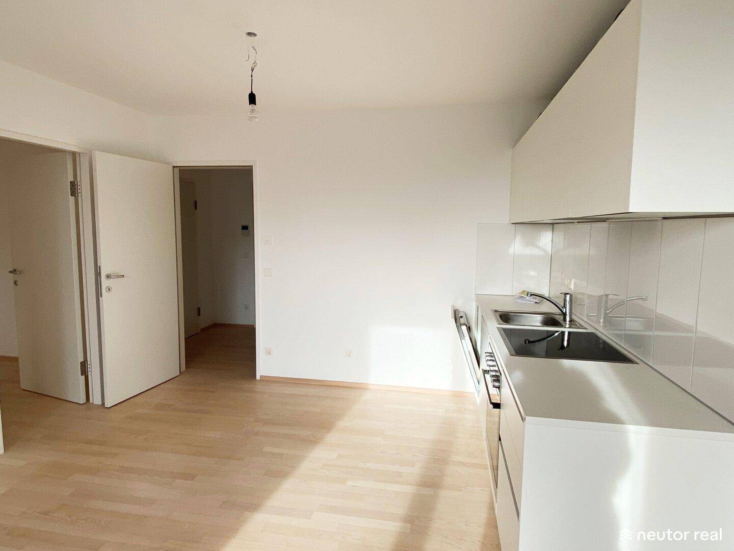Moderne Küche mit weißen Schränken, Spüle und hellem Fliesenboden im Kochbereich.