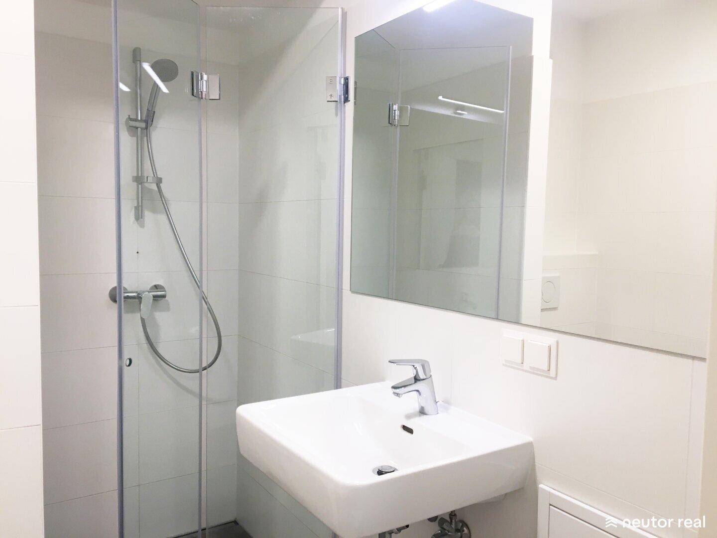 Modernes Badezimmer mit Duschkabine, Waschbecken und Spiegelschrank in hellen Fliesen.