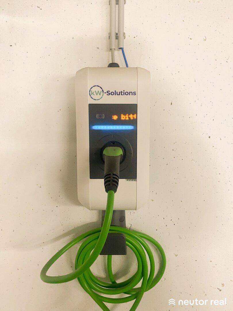 Nahaufnahme einer modernen Ladestation für Elektrofahrzeuge an einer weißen Wand in der Tiefgarage.